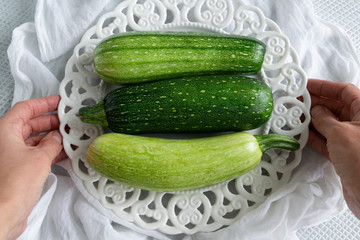 Top view of woman hands preparing fresh ripe garden zucchini. Raw organic vegetables