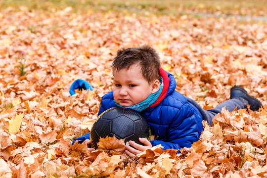 the boy is bareheaded with her hair lays on autumn yellow leaves