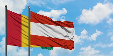 Guinea and Austria flag waving in the wind against white cloudy blue sky together. Diplomacy concept, international relations.