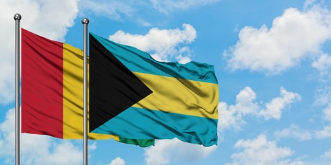 Guinea and Bahamas flag waving in the wind against white cloudy blue sky together. Diplomacy concept, international relations.