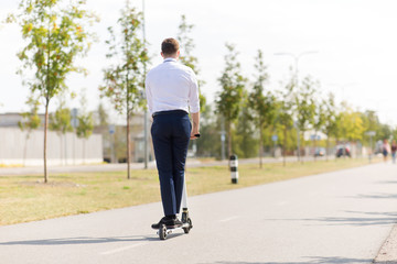 business and people and concept - young businessman riding electric scooter outdoors