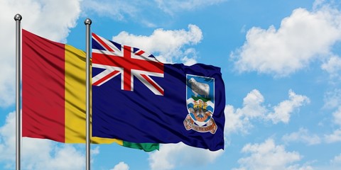 Guinea and Falkland Islands flag waving in the wind against white cloudy blue sky together. Diplomacy concept, international relations.