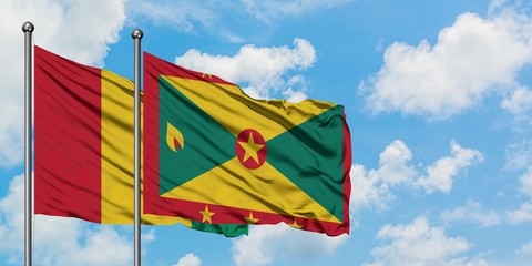 Guinea and Grenada flag waving in the wind against white cloudy blue sky together. Diplomacy concept, international relations.