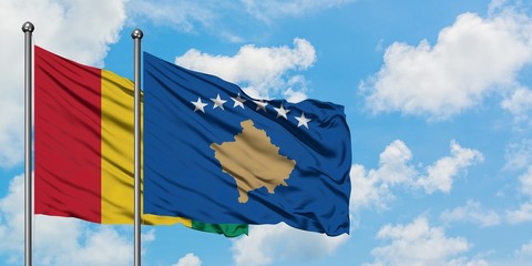 Guinea and Kosovo flag waving in the wind against white cloudy blue sky together. Diplomacy concept, international relations.