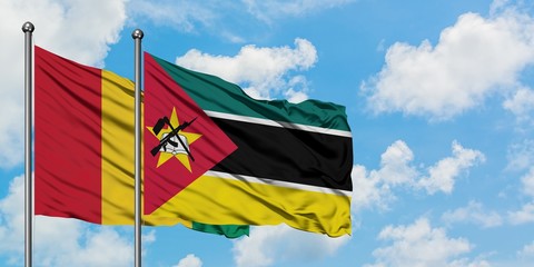 Guinea and Mozambique flag waving in the wind against white cloudy blue sky together. Diplomacy concept, international relations.