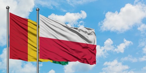 Guinea and Poland flag waving in the wind against white cloudy blue sky together. Diplomacy concept, international relations.