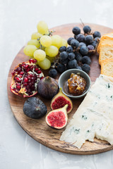 figs with cheese, grapes and honey on wooden board