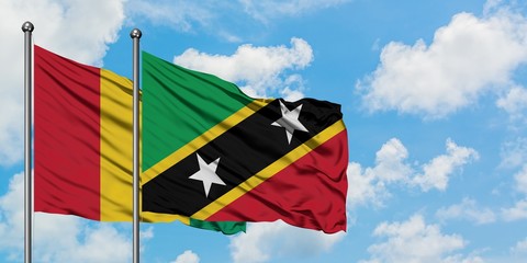 Guinea and Saint Kitts And Nevis flag waving in the wind against white cloudy blue sky together. Diplomacy concept, international relations.