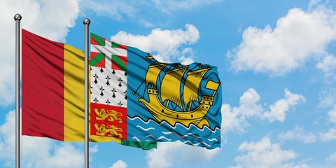 Guinea and Saint Pierre And Miquelon flag waving in the wind against white cloudy blue sky together. Diplomacy concept, international relations.
