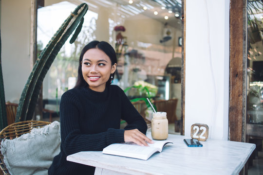 Young Asian smiling woman with notebook sitting at table