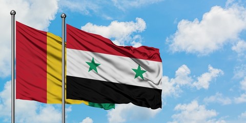 Guinea and Syria flag waving in the wind against white cloudy blue sky together. Diplomacy concept, international relations.