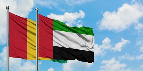 Guinea and United Arab Emirates flag waving in the wind against white cloudy blue sky together. Diplomacy concept, international relations.