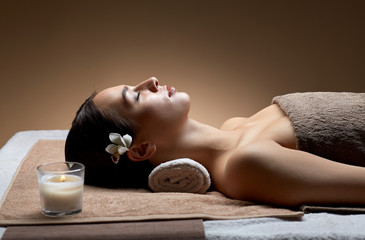 Obraz na płótnie Canvas wellness, beauty and relaxation concept - young woman lying at spa or massage parlor with burning aromatic candle