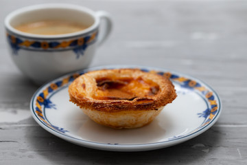 typical portuguese egg tart pastel de nata with cup of coffee on ceramic background