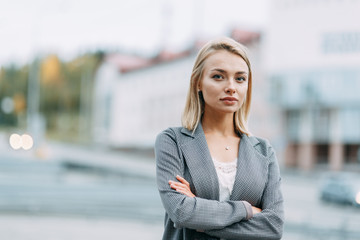 Business portrait on the background of the street. Beautiful girl with smile in town.