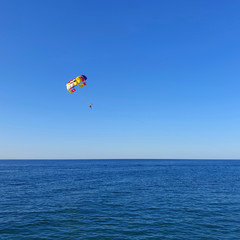 Fototapeta na wymiar A man with a parachute flies over the sea.