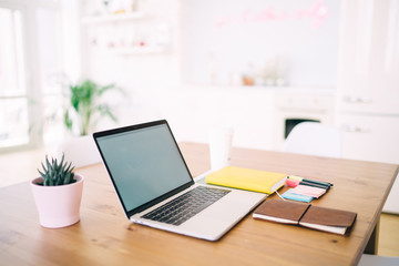 Opened laptop with white screen and office supplies on wooden table