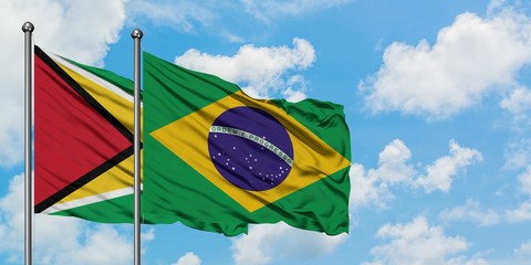 Guyana and Brazil flag waving in the wind against white cloudy blue sky together. Diplomacy concept, international relations.