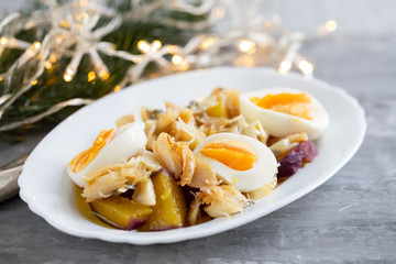 cod fish with sweet potato and boiled egg on white dish on ceramic background