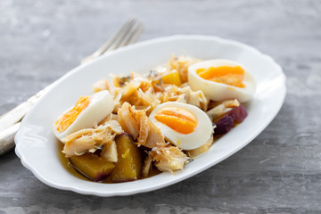 cod fish with sweet potato and boiled egg on white dish on ceramic background