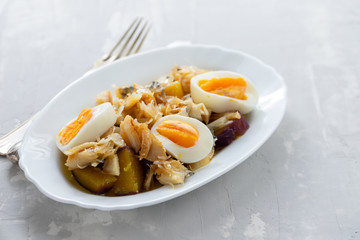 cod fish with sweet potato and boiled egg on white dish on ceramic background