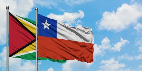 Guyana and Chile flag waving in the wind against white cloudy blue sky together. Diplomacy concept, international relations.