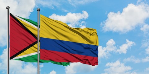 Guyana and Colombia flag waving in the wind against white cloudy blue sky together. Diplomacy concept, international relations.