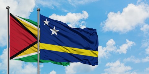 Guyana and Curacao flag waving in the wind against white cloudy blue sky together. Diplomacy concept, international relations.
