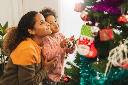 Black african mother and her cute daughter decorating christmas tree for christmas and happy new concept