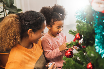 Black african mother and her cute daughter decorating christmas tree for christmas and happy new concept