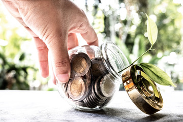 hand and Glass jar piggy bank with coins. Plan your savings, run a growing business for success and save for retirement