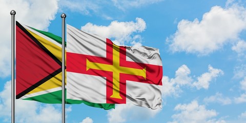 Guyana and Guernsey flag waving in the wind against white cloudy blue sky together. Diplomacy concept, international relations.