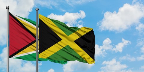 Guyana and Jamaica flag waving in the wind against white cloudy blue sky together. Diplomacy concept, international relations.