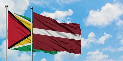 Guyana and Latvia flag waving in the wind against white cloudy blue sky together. Diplomacy concept, international relations.