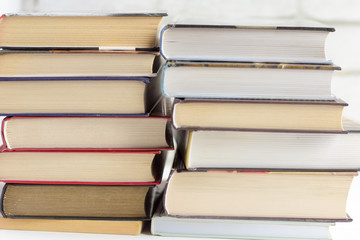 Books for reading in hardcover piles are lying on the table.