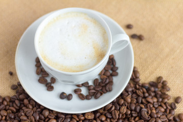 foam coffee in a white Cup and coffee beans on the table, selective focus