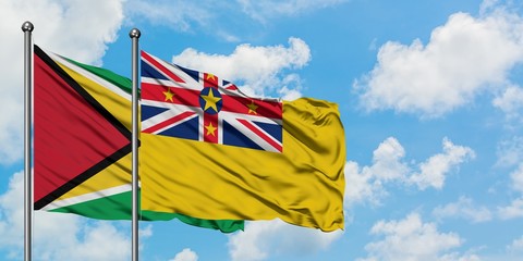Guyana and Niue flag waving in the wind against white cloudy blue sky together. Diplomacy concept, international relations.
