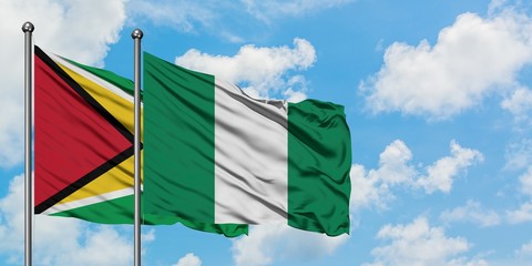 Guyana and Nigeria flag waving in the wind against white cloudy blue sky together. Diplomacy concept, international relations.