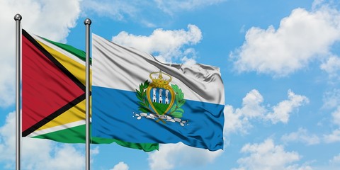 Guyana and San Marino flag waving in the wind against white cloudy blue sky together. Diplomacy concept, international relations.