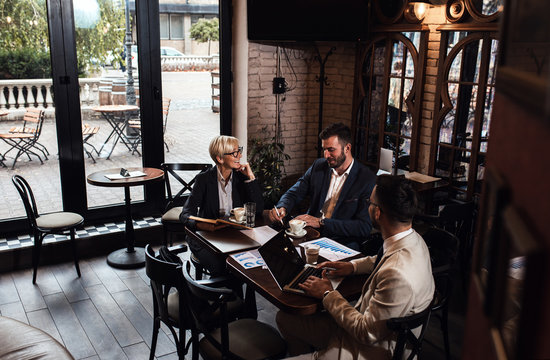 Senior businesswoman holding a meeting with her younger colleagues at office cafeteria.