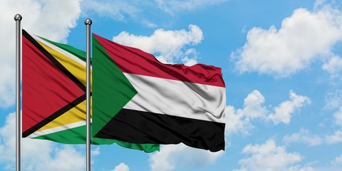 Guyana and Sudan flag waving in the wind against white cloudy blue sky together. Diplomacy concept, international relations.