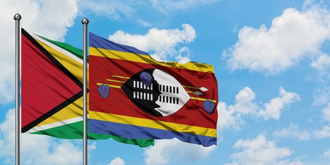 Guyana and Swaziland flag waving in the wind against white cloudy blue sky together. Diplomacy concept, international relations.