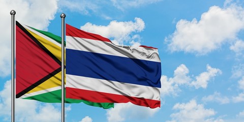 Guyana and Thailand flag waving in the wind against white cloudy blue sky together. Diplomacy concept, international relations.