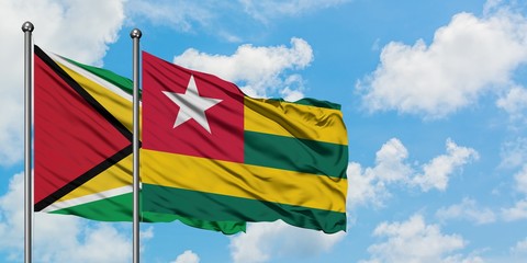 Guyana and Togo flag waving in the wind against white cloudy blue sky together. Diplomacy concept, international relations.