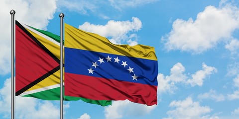 Guyana and Venezuela flag waving in the wind against white cloudy blue sky together. Diplomacy concept, international relations.