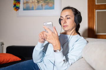 Fototapeta premium Young Spanish woman listening to music at home with headphones