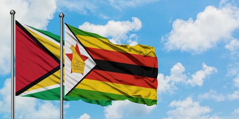 Guyana and Zimbabwe flag waving in the wind against white cloudy blue sky together. Diplomacy concept, international relations.