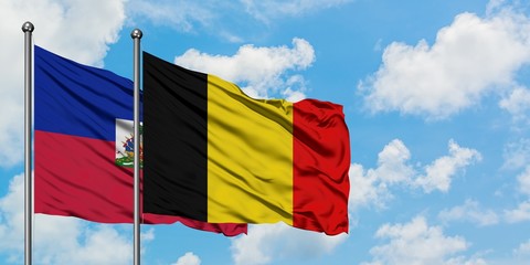 Haiti and Belgium flag waving in the wind against white cloudy blue sky together. Diplomacy concept, international relations.