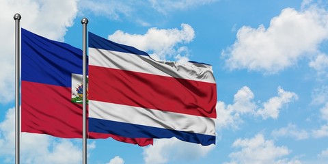 Haiti and Costa Rica flag waving in the wind against white cloudy blue sky together. Diplomacy concept, international relations.