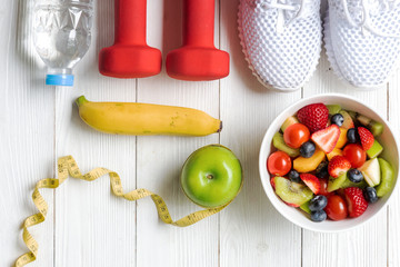 Diet and weight loss for healthy care with  fitness equipment, fresh water and fruit healthy, green apple, banana, cherry on white wooden background top view.  Healthy Concept.